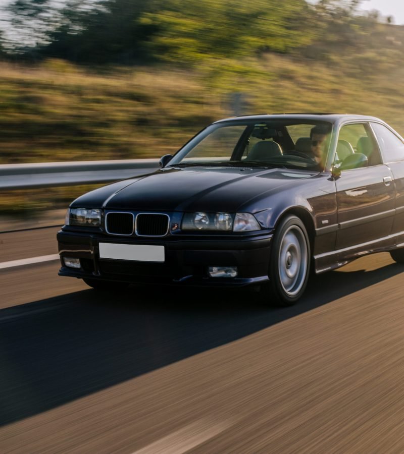 vintage-sedan-car-driving-sunlight-road